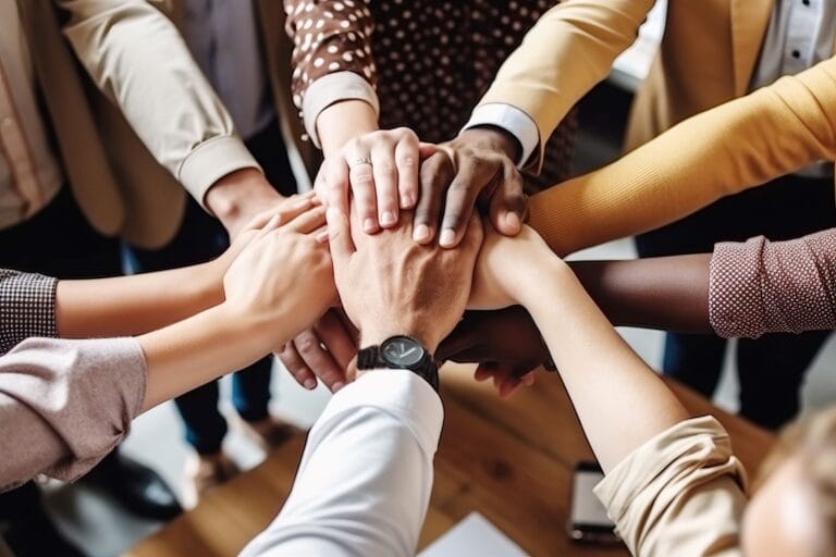 team of people in circle with hands reaching into centre